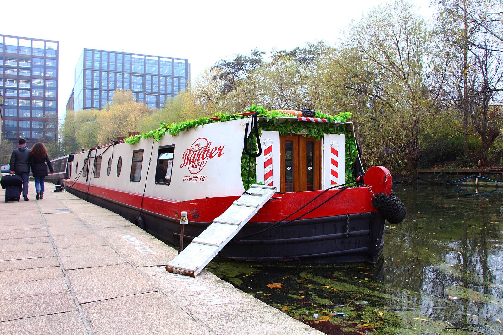 Plovoucí barbershop na lodi s pruhovanými sloupy na kanálu Regent's Canal v Londýně
